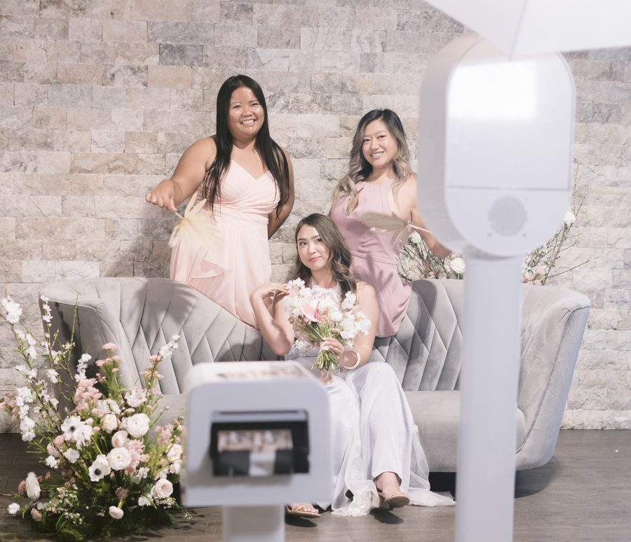A bride and two bridesmaids posing in front of the open-air booth