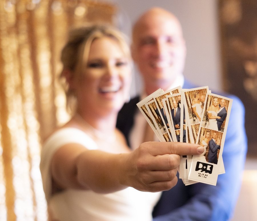 A newlywed couple holding up a fan of their custom photo strips